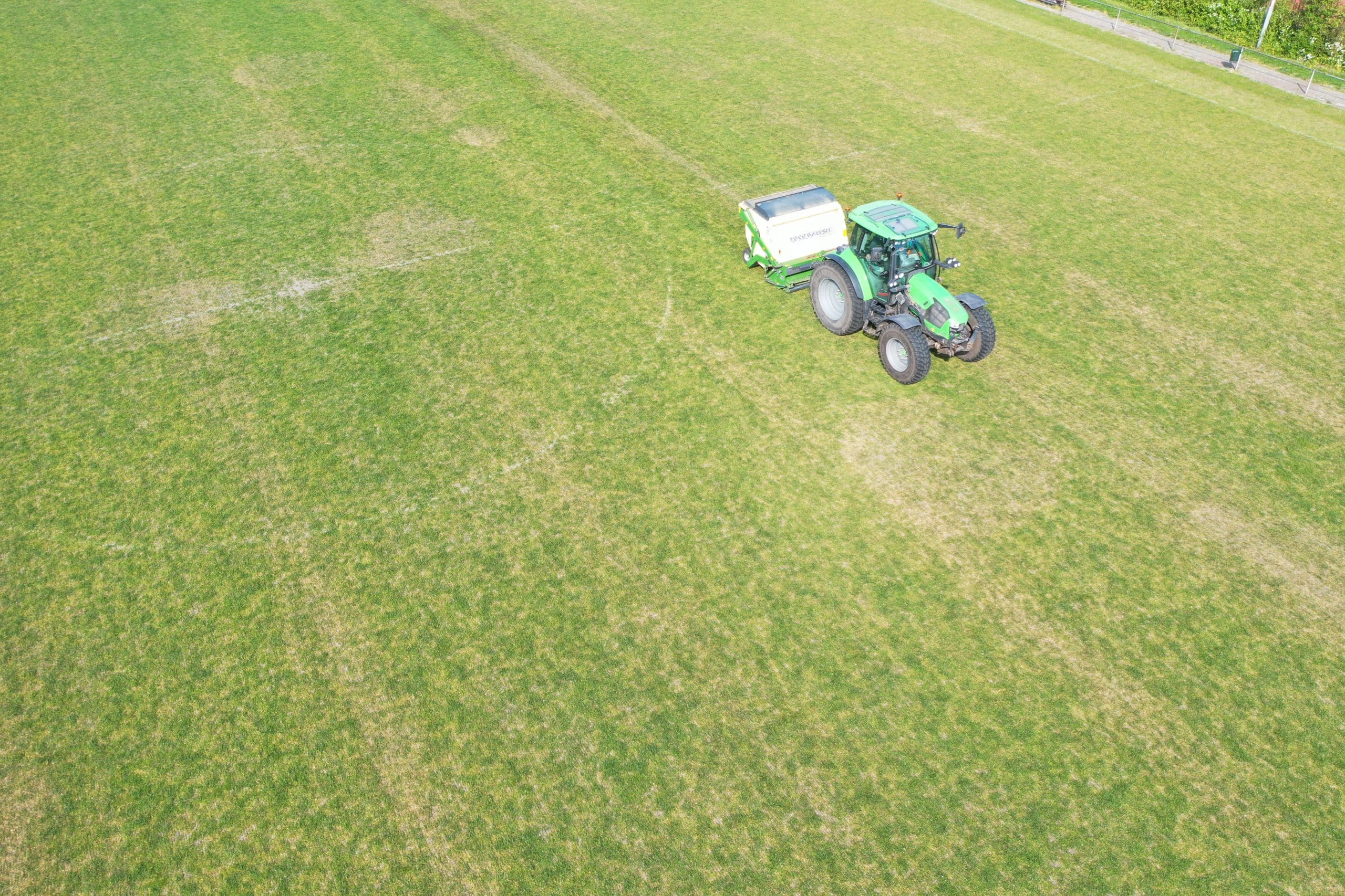Tractor verticuteert een droog sportveld ter voorbereiding op doorzaaien